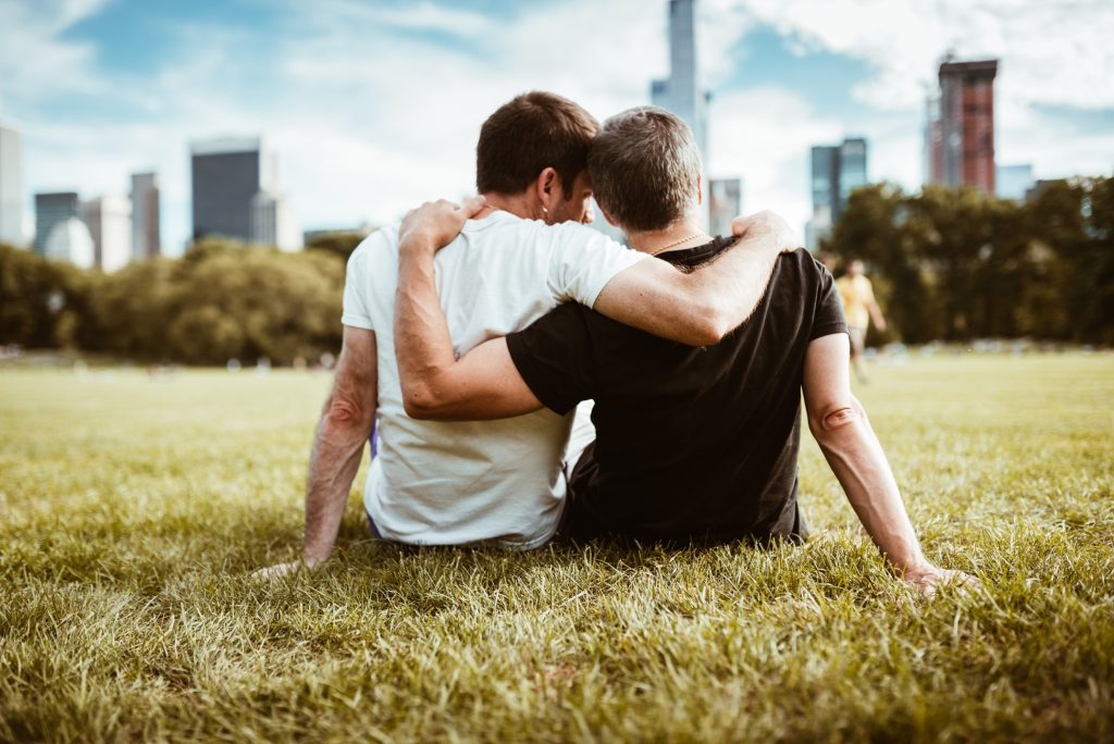 LGBT+_guys sitting in grass looking at city