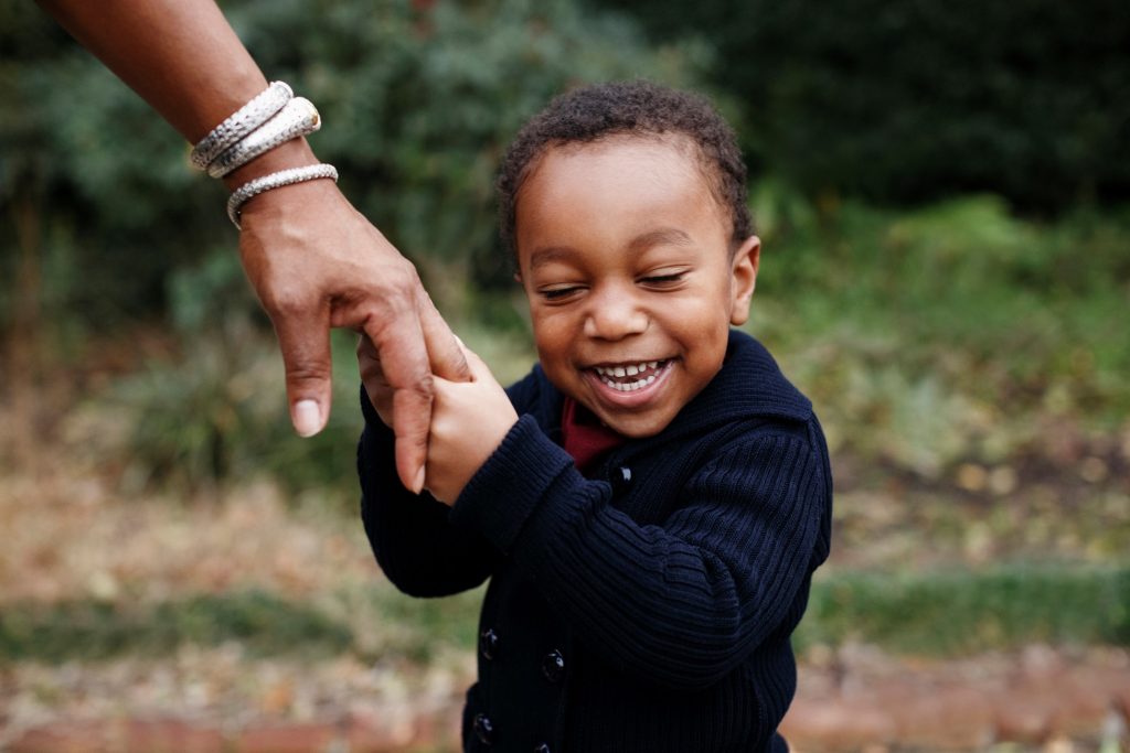 toddler boy smiling_holding mom hand